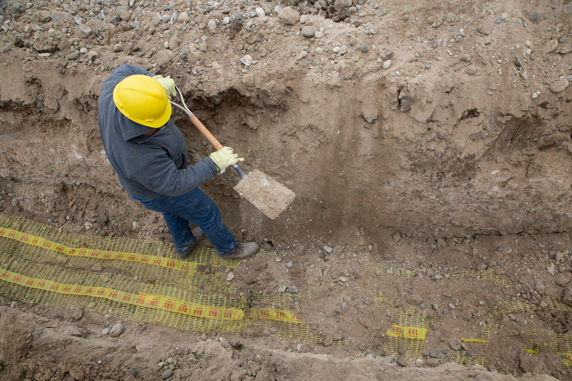 Worker excavating underground utility trench