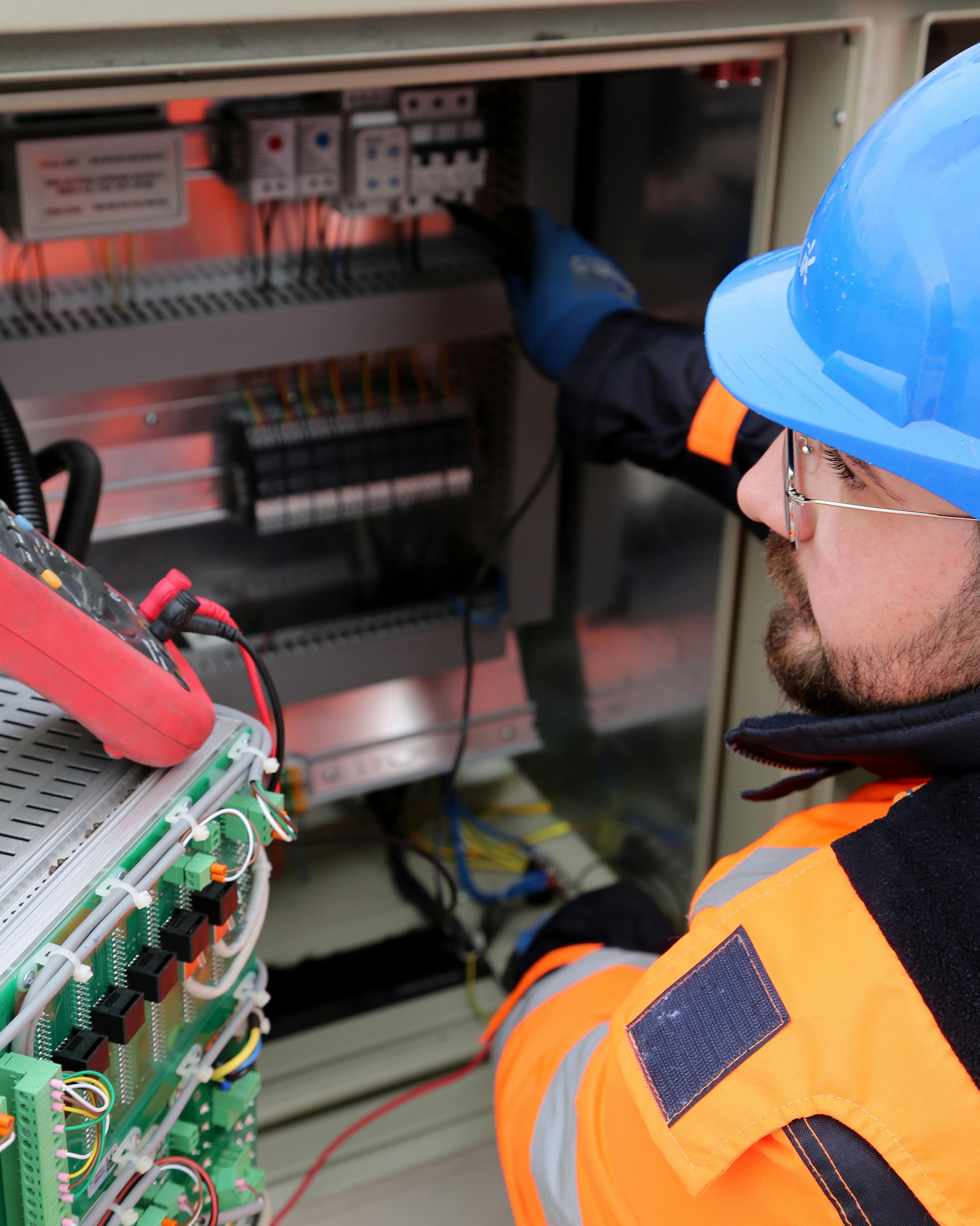 Technician with relay test set at control panel